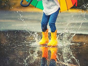 Child wearing wellies splashing in a puddle