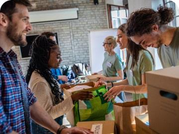 People donating items in bag and boxes at a collection table