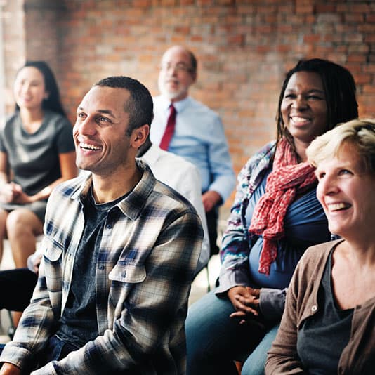 A gathering of individuals seated in a room, participating in a discussion or meeting