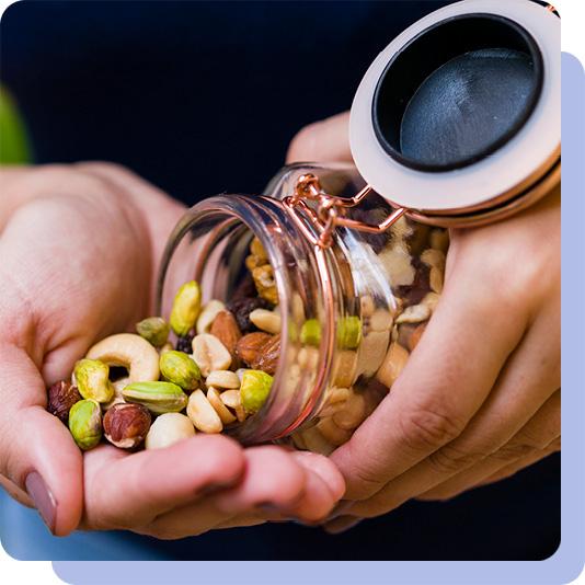 A person pouring mixed nuts from a jar into their hand