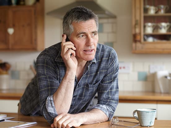 Man making a phone call at home in kitchen