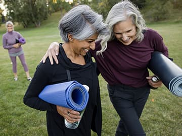 Two women smiling after outside yoga class