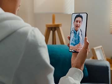 Person holding smartphone during a video appointment with a GP