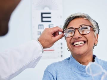 Lady trying on glasses in opticians
