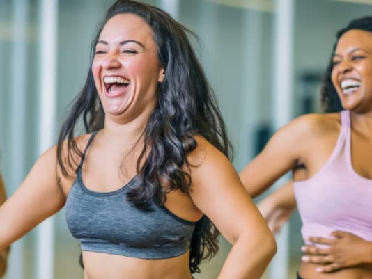 Two ladies laughing and dancing at exercise class