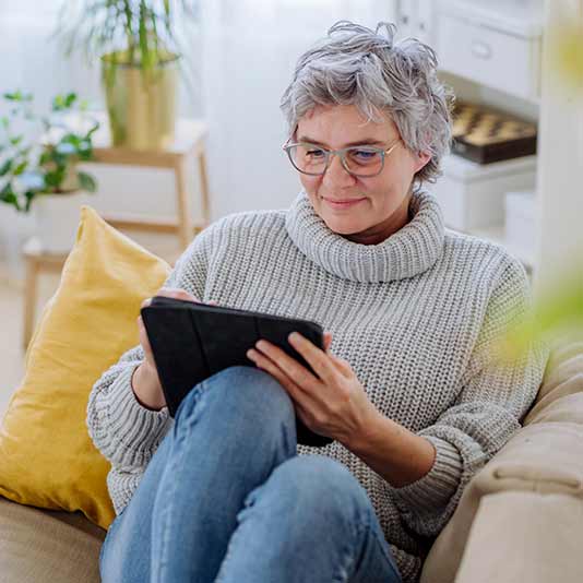 Lady using iPad on sofa at home