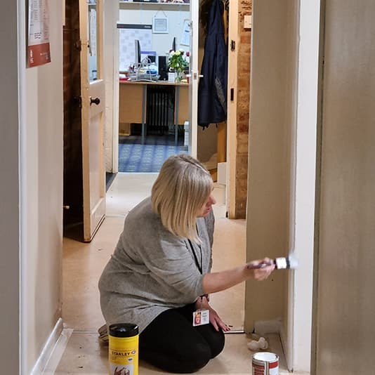 Simplyhealth employee painting a door frame using white paint