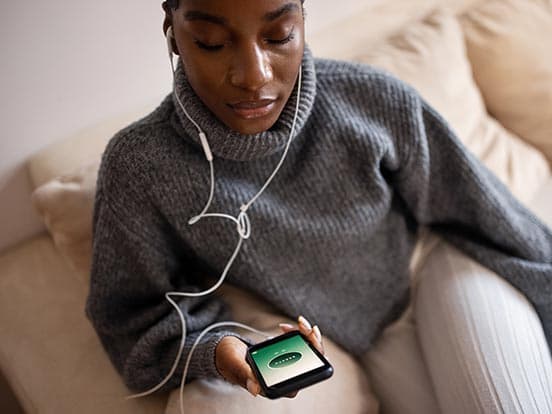 Woman holding a smartphone using headphone to listen to a meditation app