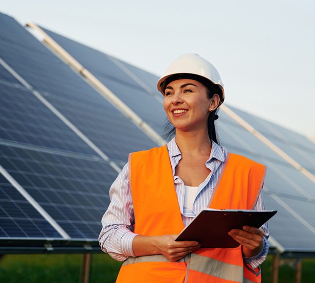 Woman industrial worker standing in front of large solar panels